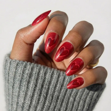 Sent with Love press-on nails featuring romantic red heart design on almond-shaped nails, styled on natural hands for feminin