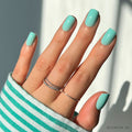 Soft teal press-on nails with glossy finish showcasing elegant almond nail shape on white background